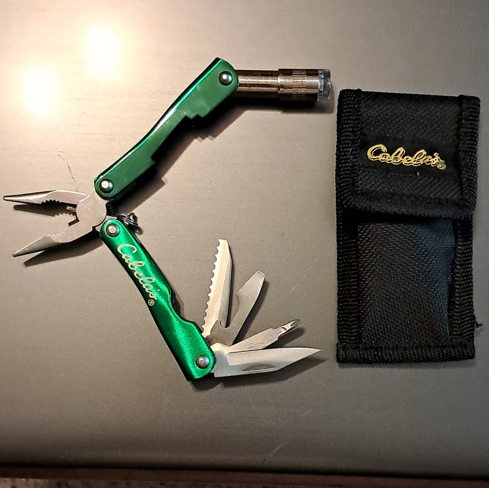 Cabela’s Green/Silver 6-in-1 Multi-Tool Pliers, 2.25″ SS Blade w/ Sheath