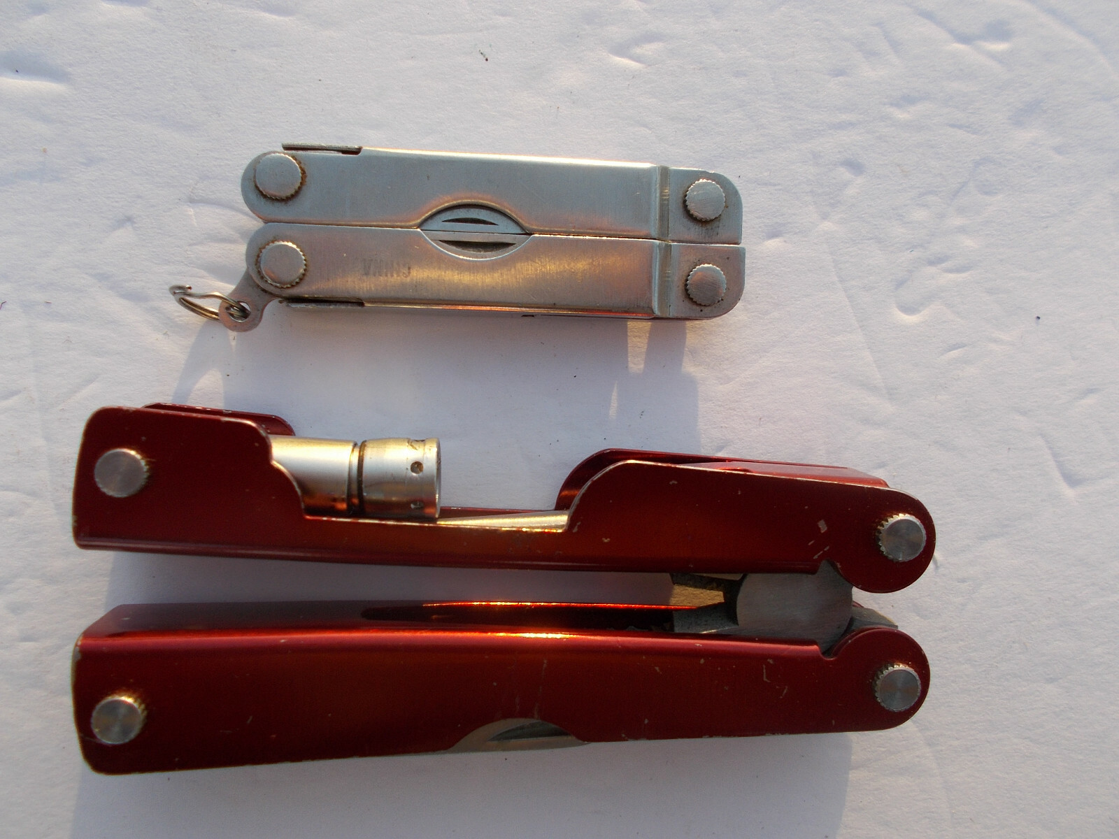 Lot of (2) multi tools – 1 Durex advertising silver tone and 1 unbranded red