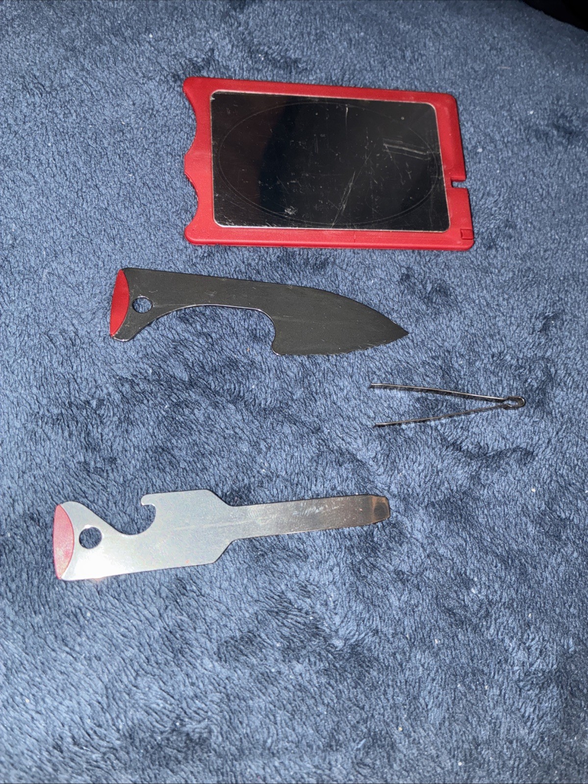 Red credit card size multitool has knife, toothpick, tweezers, and other Items