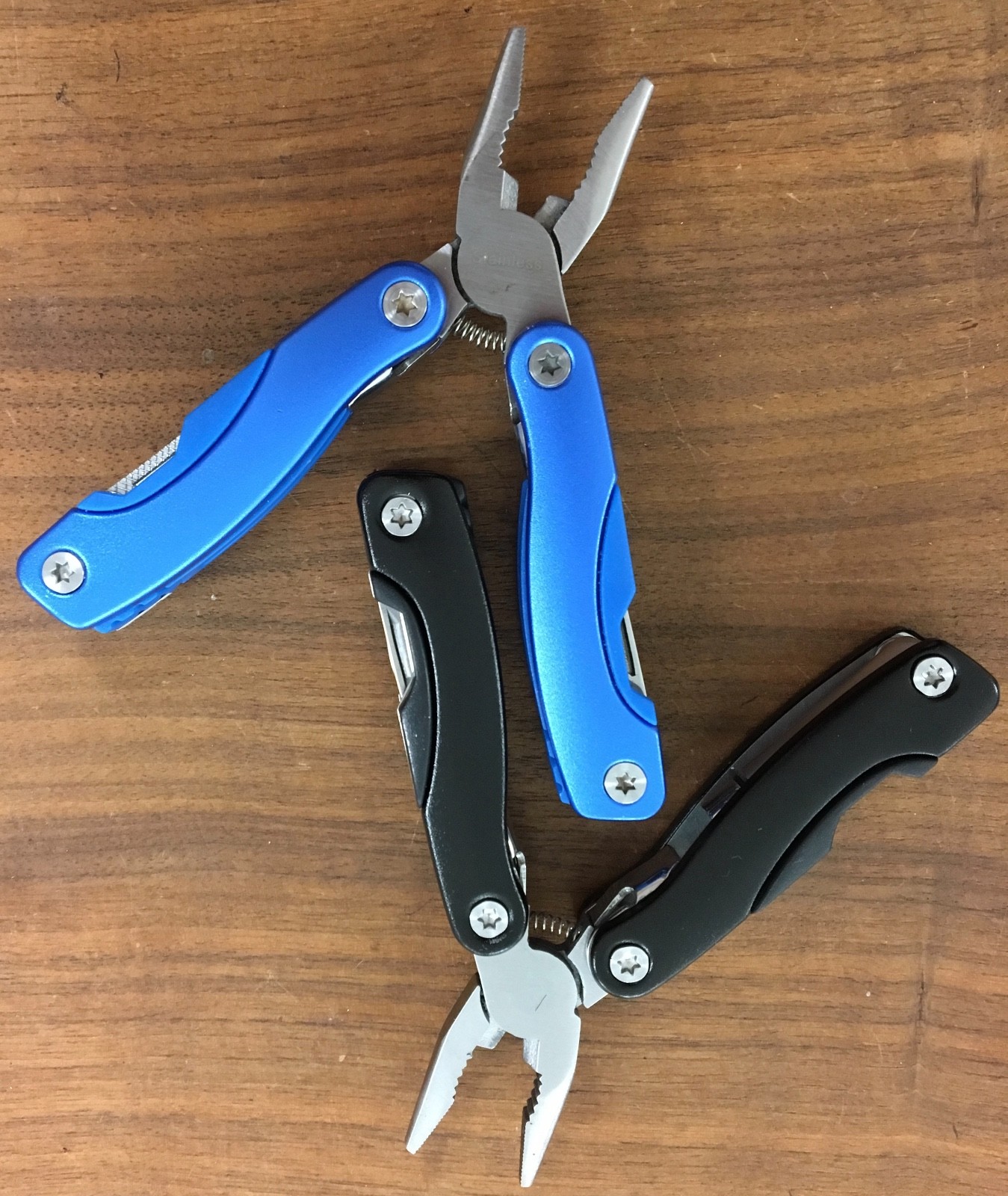 Pair of multi tools, one blue, the other black, with sheaths. Camp, hunt, crafts