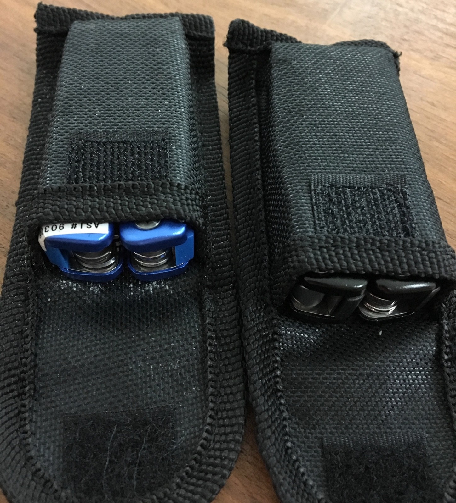 Pair of multi tools, one blue, the other black, with sheaths. Camp, hunt, crafts
