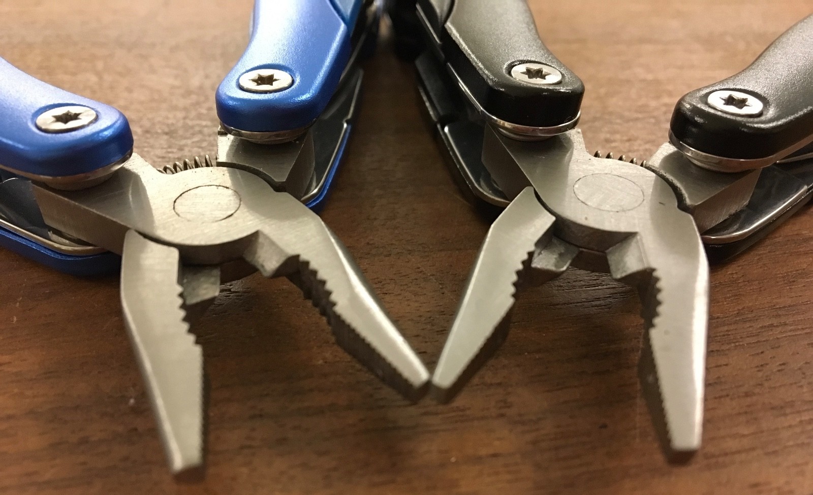 Pair of multi tools, one blue, the other black, with sheaths. Camp, hunt, crafts