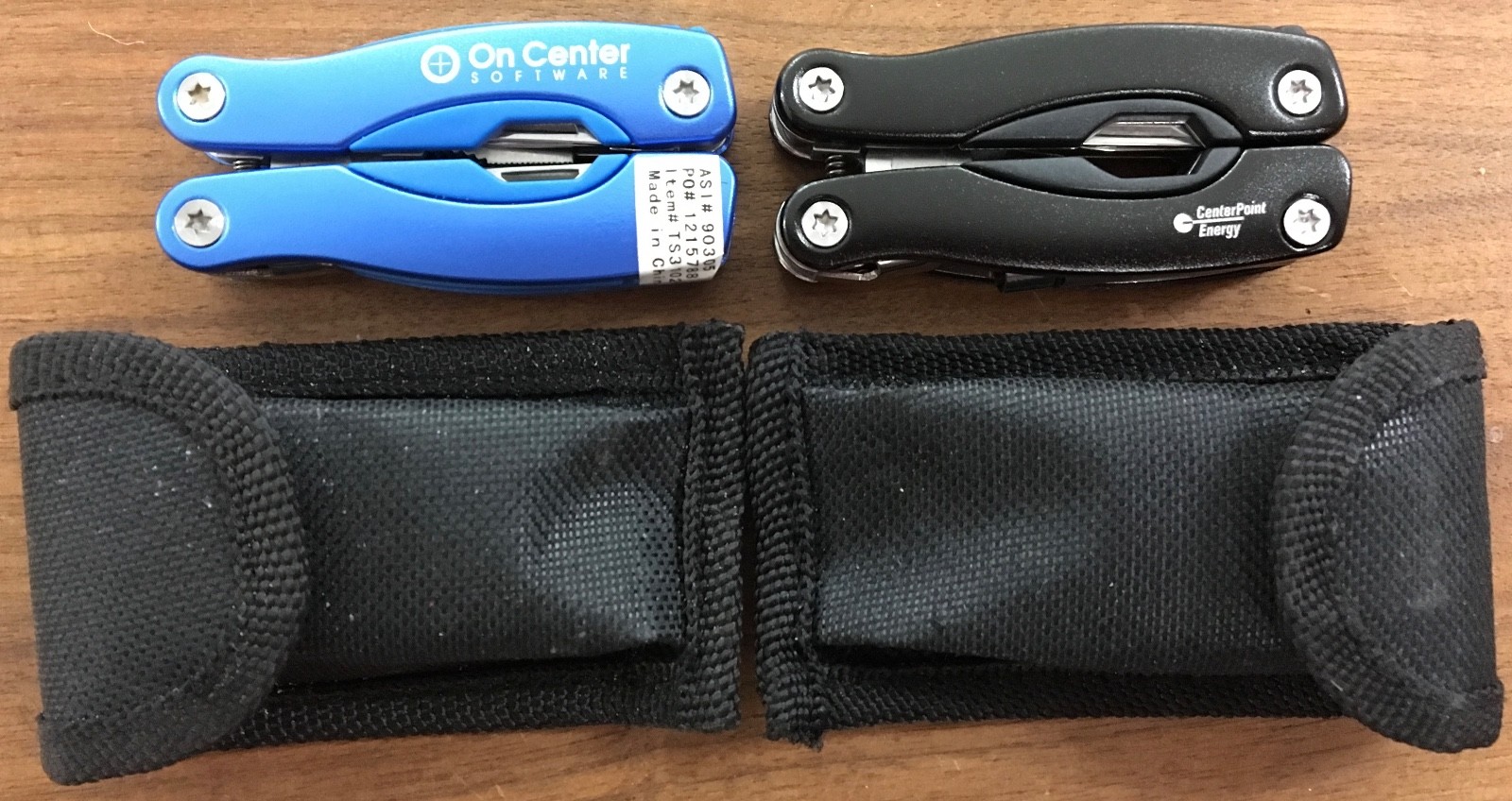 Pair of multi tools, one blue, the other black, with sheaths. Camp, hunt, crafts