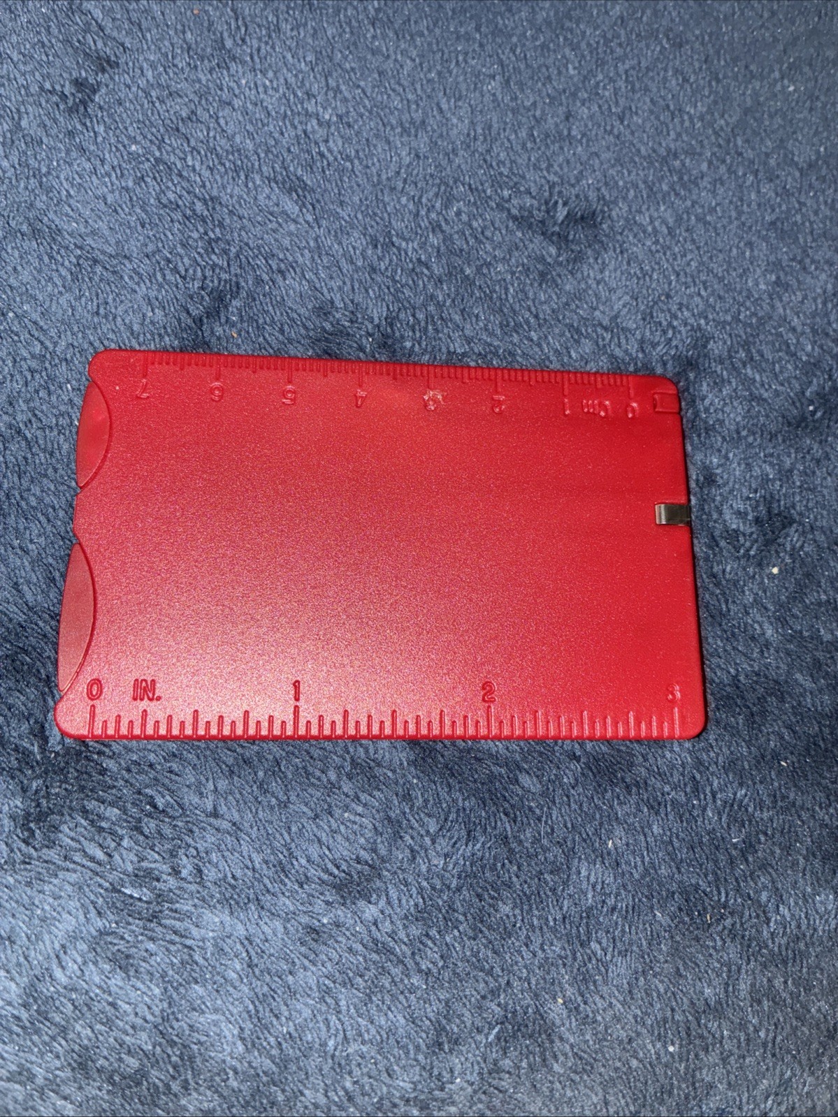 Red credit card size multitool has knife, toothpick, tweezers, and other Items