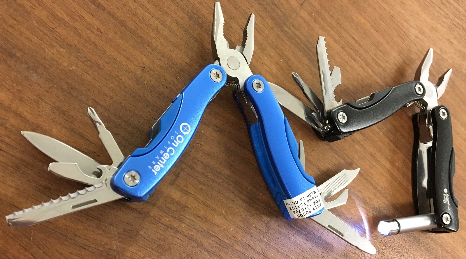 Pair of multi tools, one blue, the other black, with sheaths. Camp, hunt, crafts