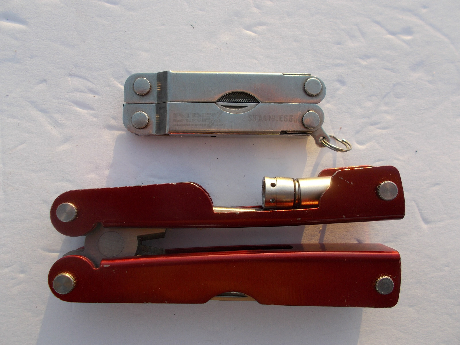 Lot of (2) multi tools – 1 Durex advertising silver tone and 1 unbranded red